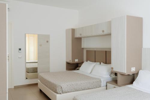 two beds in a room with white walls at Hotel Caravel in Vasto