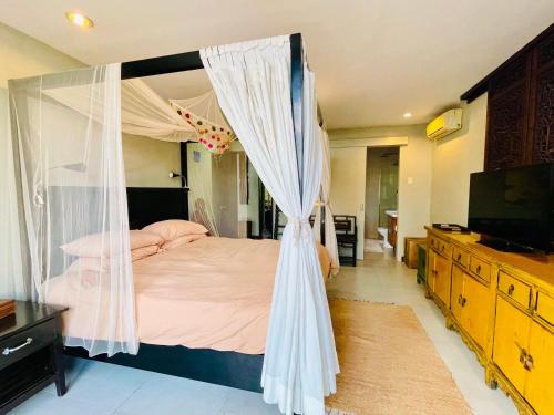 a bedroom with a canopy bed and a television at 3 BedRoom Penthouse in Boracay Station 1 in Boracay