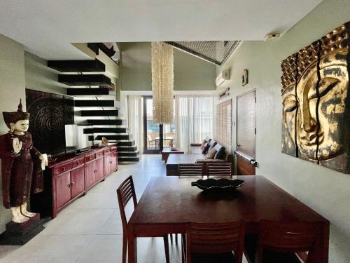a living room with a dining room table and stairs at 3 BedRoom Penthouse in Boracay Station 1 in Boracay