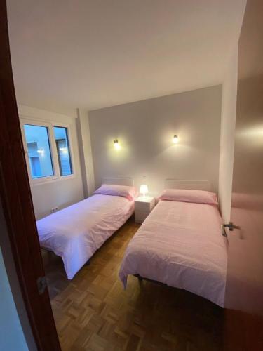two beds in a room with two windows at Sego Apartments II in Segovia