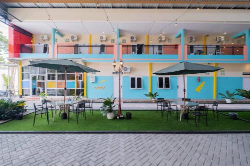 a building with tables and umbrellas in front of it at Sans WM Hotel Blitar in Blitar