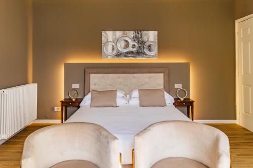 a bedroom with a large bed with two chairs at Villa Antica Colonia SPA & Wellness in Pettenasco