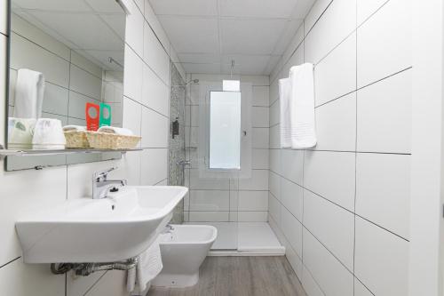 a white bathroom with a sink and a toilet at Hotel Goya in Crevillente