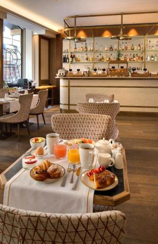- une table avec des aliments pour le petit-déjeuner dans un restaurant dans l'établissement Rochester Champs Elysees, à Paris
