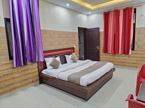 a bedroom with a bed with purple and red curtains at Swas Tika Homes Near Wave City Center Noida in Noida