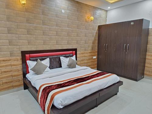 a bedroom with a large bed and a wooden wall at Swas Tika Homes Near Wave City Center Noida in Noida