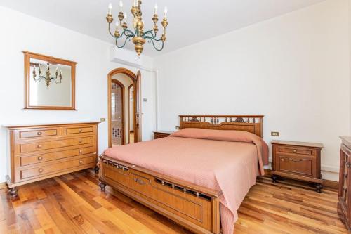 a bedroom with a bed and a dresser and a chandelier at GOLDEN LUXE - Grand Villa with Exlusive Garden in Camaiore