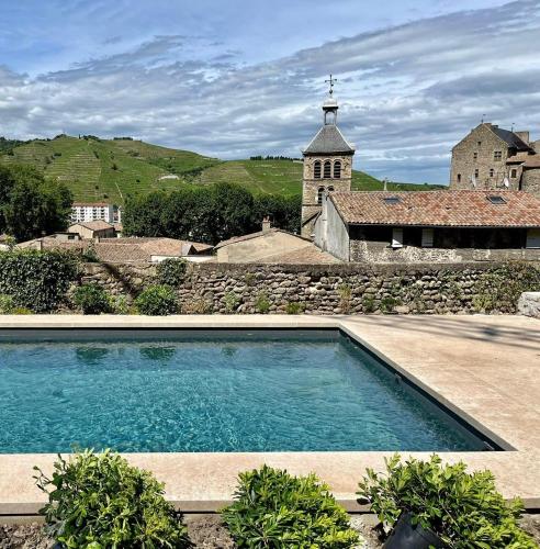 - une piscine en face d'un bâtiment avec une église dans l'établissement Hôtel de la Villeon, à Tournon-sur-Rhône