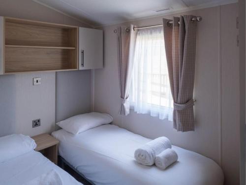 two twin beds in a small room with a window at Pinewoods Park Style no.1 - sleeps 6 – no dogs in Wells next the Sea