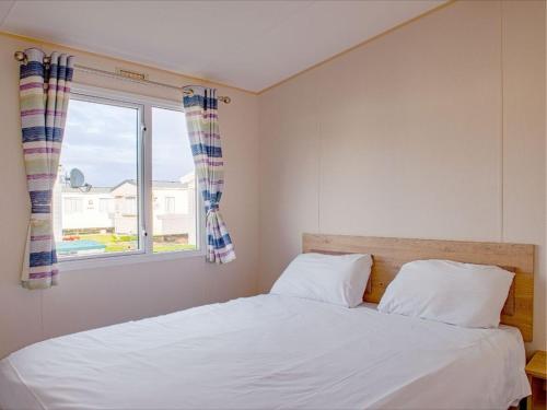 a bedroom with a white bed and a window at Pinewoods Park Compact sleeps 6 – no dogs in Wells next the Sea