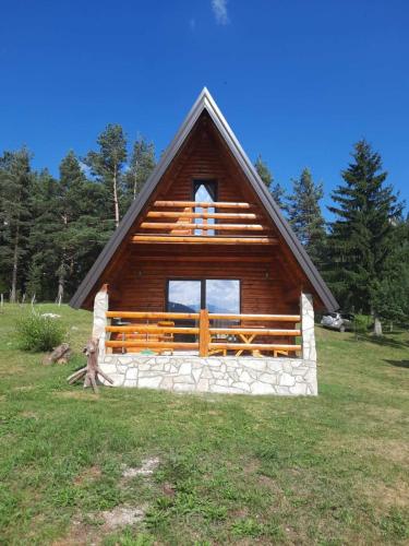 a log cabin with a large window in a field at Vila Dajana Zminica in Žabljak