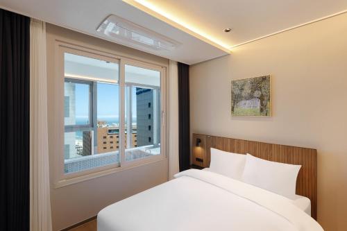 a bedroom with a bed and a large window at NewCZ Haeundae Residence in Busan