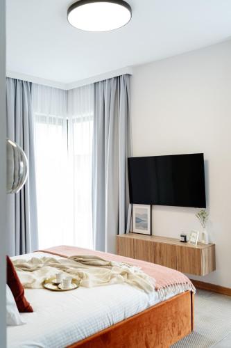 a bedroom with a bed and a flat screen tv at Sol Marina Resort Wyspa Sobieszewska I - LoftAffair Collection in Wiślinka