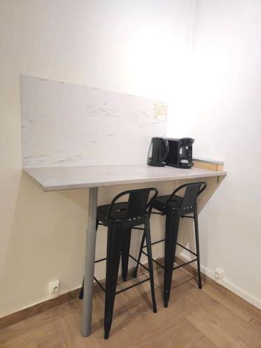 - une table avec deux chaises et un four micro-ondes dans l'établissement 712 Studio à deux pas du métro et de Paris 20ème, à Bagnolet