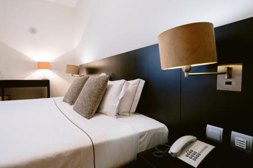 a hotel room with a bed with a phone and a telephone at Hotel Conde de Agueda in Águeda