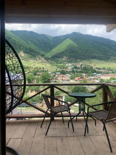 a table and chairs on a balcony with a view at COTTAGE cozy side in Mestia
