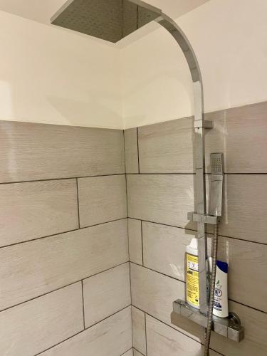 une douche dans une salle de bain avec du carrelage blanc dans l'établissement Entre deux rivières, à Montolieu