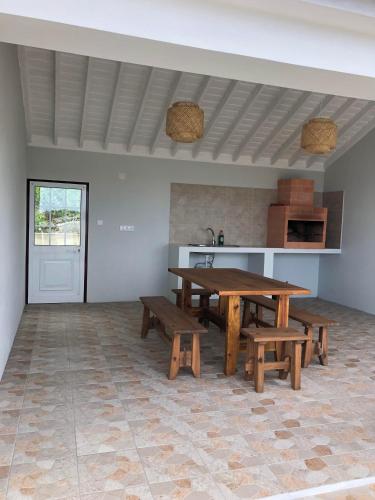 a room with a table and benches and a kitchen at Casa da Baía da Feteira in Lajes do Pico