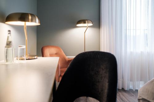 a room with a table and two lamps and a chair at Mercure Hotel Pforzheim in Pforzheim