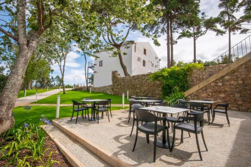 a patio with tables and chairs in a park at Palácio dos Marqueses in Mafra