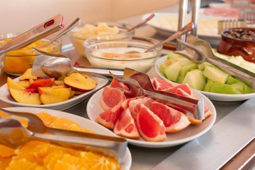 a buffet with plates of fruit and tongs on a table at Corfu Maris in Benitses