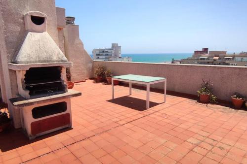 a patio with a table and a grill on a balcony at Amplio apartamento con vista al mar en El Perelló in El Perellonet