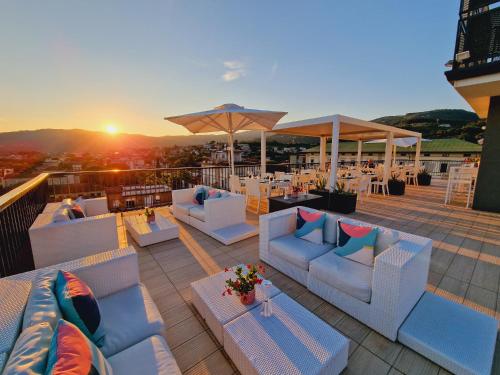 a rooftop deck with couches and tables and a sunset at LHP Hotel Montecatini Palace & SPA in Montecatini Terme