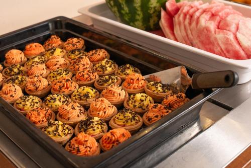 a tray of cupcakes in a bin next to watermelon at Corfu Maris in Benitses