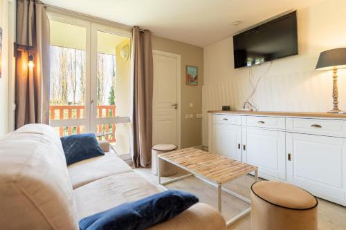 un salon avec un canapé blanc et une télévision dans l'établissement 6-person flat with swimming pool tennis court and car park 157, à Le Touquet-Paris-Plage