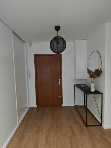 Cette chambre dispose d'une porte en bois, d'une table et d'un miroir. dans l'établissement Les Glières - Appartement confortable et au calme, à Annecy