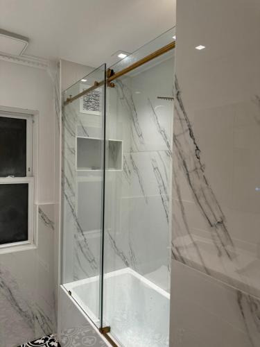 a shower with a glass door in a bathroom at La Casa Bonita Near NYC in Yonkers