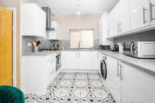 a kitchen with white cabinets and a tile floor at Cozy 3-bed house ideal for families and contractors with Netflix 7 miles for Birmingham City Centre in Oldbury