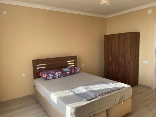 Un dormitorio con una cama y un armario de madera. en Kalendere, en Batumi