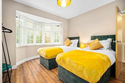 two beds in a bedroom with yellow sheets at Cozy 3-bed house ideal for families and contractors with Netflix 7 miles for Birmingham City Centre in Oldbury