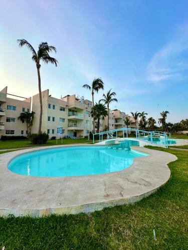 a large blue pool with palm trees and condos at Departamento en Pb frente a la alberca in Acapulco