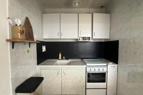 une cuisine avec des armoires blanches, un évier et une cuisinière dans l'établissement Comfortable apartment with sea view, à Fleury
