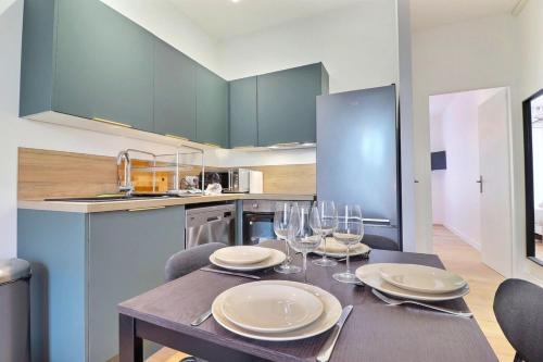 une cuisine avec une table avec des assiettes et des verres à vin dans l'établissement The Tavira - Magnificent renovated T2 apartment - Villeurbanne, à Villeurbanne