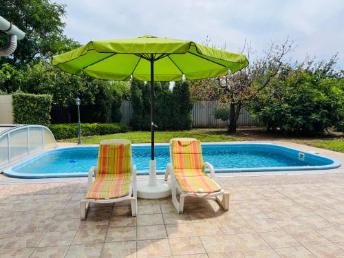 two chairs and an umbrella next to a swimming pool at Flower Tisza Vendégház in Tiszafüred