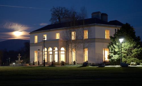 a large white building at night with the moon behind it at Tulfarris Hotel and Golf Resort in Blessington