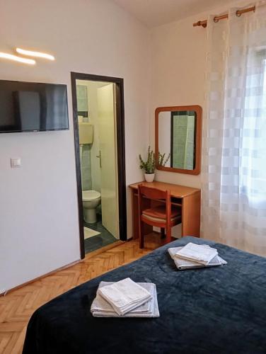a bedroom with a bed and a desk and a mirror at Rooms Helena in Krk