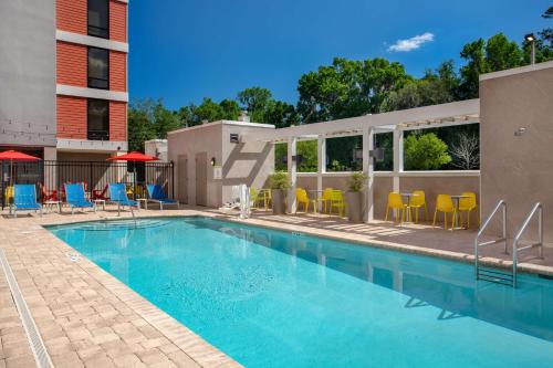 a swimming pool with blue and yellow chairs next to a building at Home2 Suites By Hilton Gainesville in Gainesville