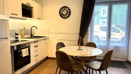 une cuisine avec une table et des chaises et une horloge au mur dans l'établissement Le Refuge contemporain, à Lorient