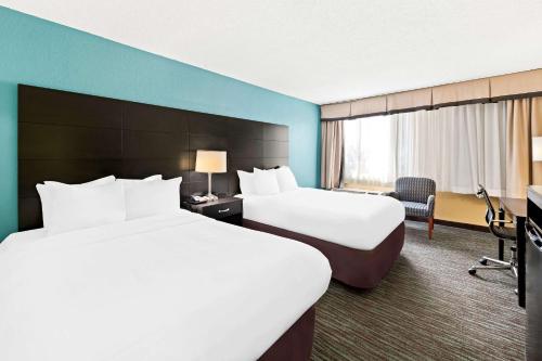 a hotel room with two beds and a television at Quality Inn Dayton Airport in Englewood