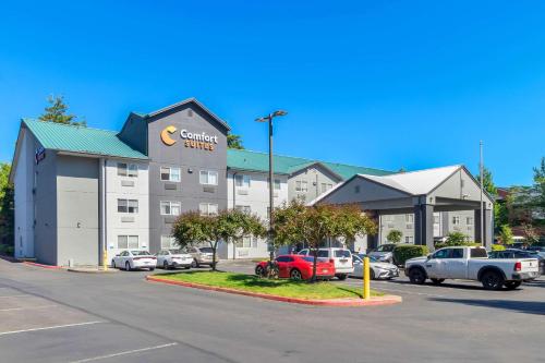 a hotel with cars parked in a parking lot at Comfort Suites Portland Airport in Portland