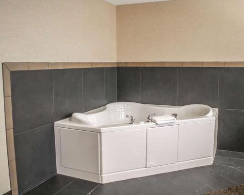 a white bath tub in a bathroom with gray tiles at Comfort Inn & Suites Wadsworth in Wadsworth