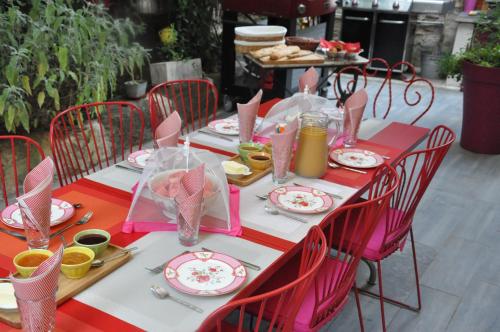 a table with red chairs and pink and white plates at No2 La Place in Tourbes