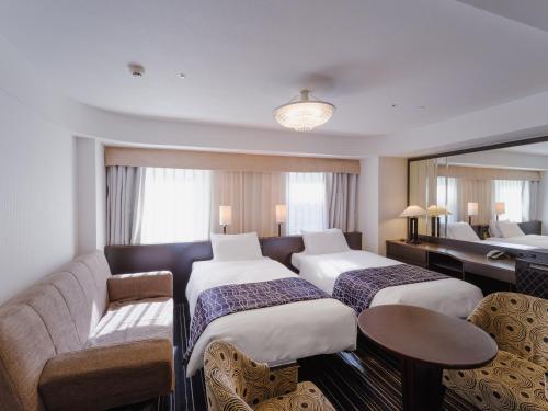a hotel room with two beds and a couch at APA Hotel Keisei Narita Ekimae in Narita