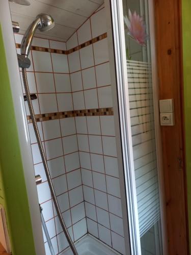 une douche dans une salle de bain avec du carrelage blanc dans l'établissement Roulotte au pied du Mont Saint Michel, à Pontorson