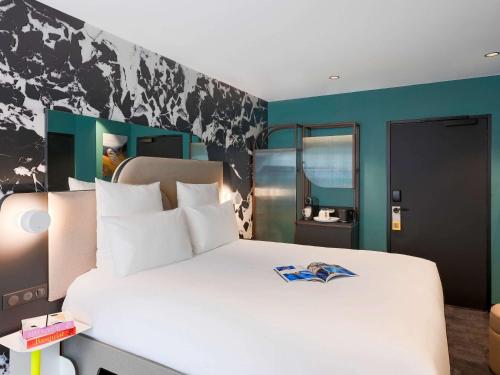 a bedroom with a large white bed and blue walls at Tribe Paris La Defense Esplanade in Courbevoie