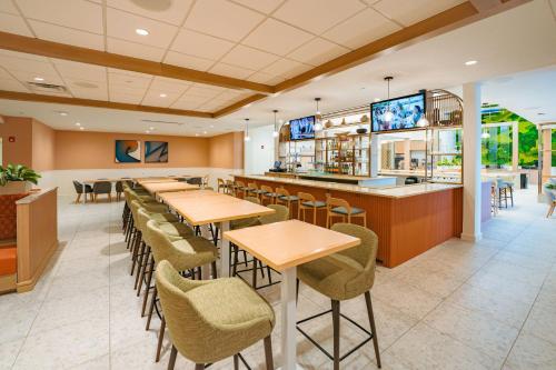 a restaurant with tables and chairs and a bar at Embassy Suites By Hilton Orlando Sunset Walk in Kissimmee